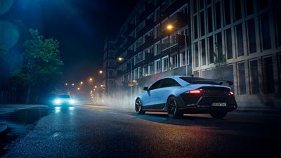 Achteraanzicht Hyundai IONIQ 6 N, rijdend door een stad bij nacht.