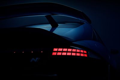 Close-up of Hyundai IONIQ 6N rear spoiler and illuminated tail lights highlighting sporty design.”