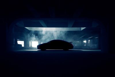 Silhouette of a Hyundai IONIQ 6 N parked in a dimly lit garage with smoke in the background.