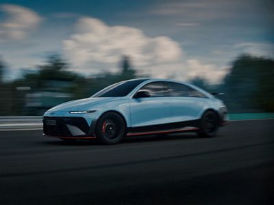 Hyundai IONIQ 6 N in motion, showcasing speed and agility against a blurred backdrop of a racing environment.