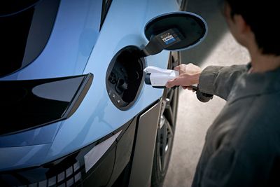 Nahaufnahme einer Person, die ein Ladekabel in den Ladeanschluss des Hyundai IONIQ 6 N einsteckt.