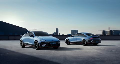 Two Hyundai IONIQ 6N cars parked on a rooftop with a city skyline in the background.