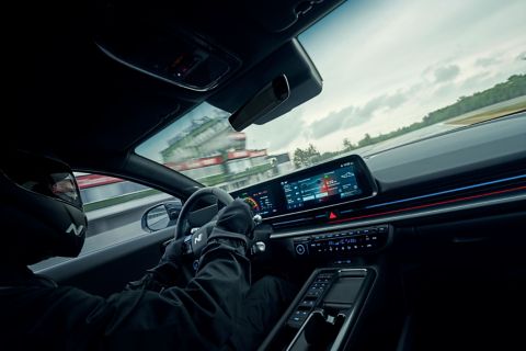 Sport driver operating Hyundai IONIQ 6 N high-performance EV with close-up of digital dashboard and interior cockpit