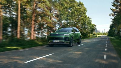 Hyundai IONIQ 9 electric SUV driving on a tree-lined road