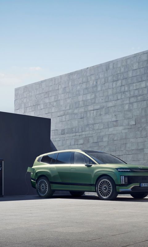 Front view of the Hyundai IONIQ 9, plugged in for charging outside the building.