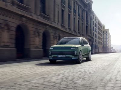 Ein Hyundai IONIQ 9 fährt über Pflastersteine in einer Stadt.