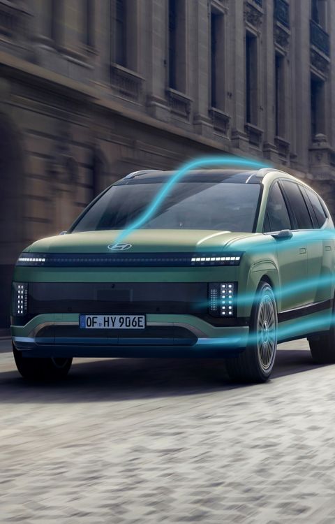 Hyundai IONIQ 9 driving through a city street with an aerodynamic flow graphic.