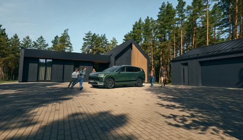 Hyundai IONIQ 9 sett fra siden foran et hus med barn som løper rundt. Foto.
