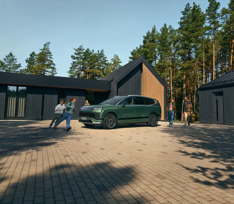 Rodicia a deti okolo zeleneho Hyundai IONIQ 9 pred rodinnym domom