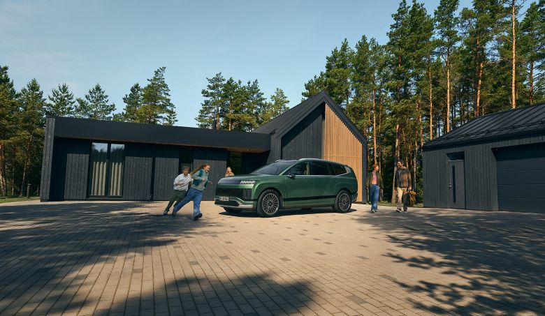 Rodicia a deti okolo zeleneho Hyundai IONIQ 9 pred rodinnym domom