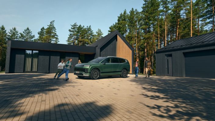 Rodicia a deti okolo zeleneho Hyundai IONIQ 9 pred rodinnym domom