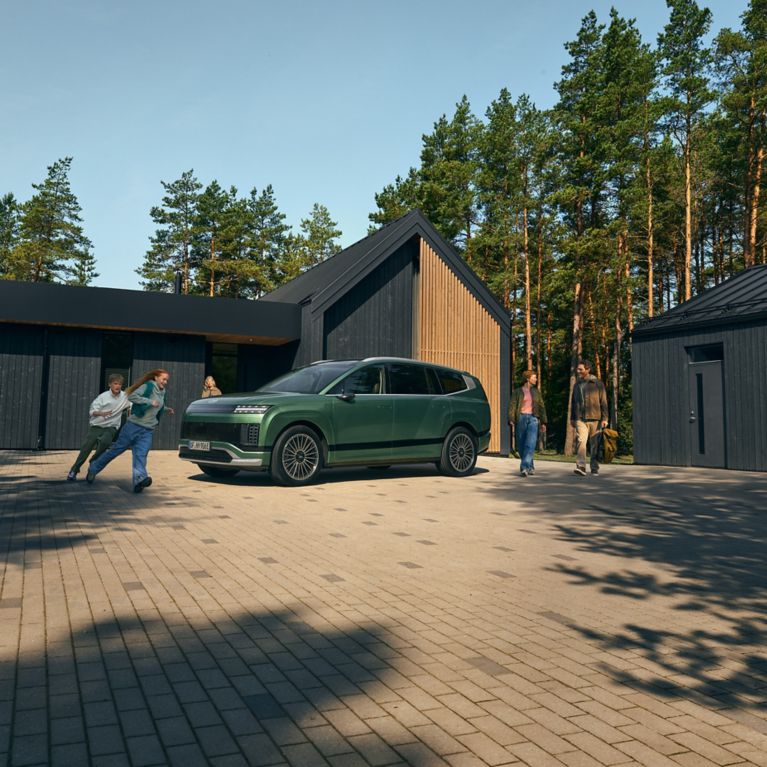 Rodicia a deti okolo zeleneho Hyundai IONIQ 9 pred rodinnym domom