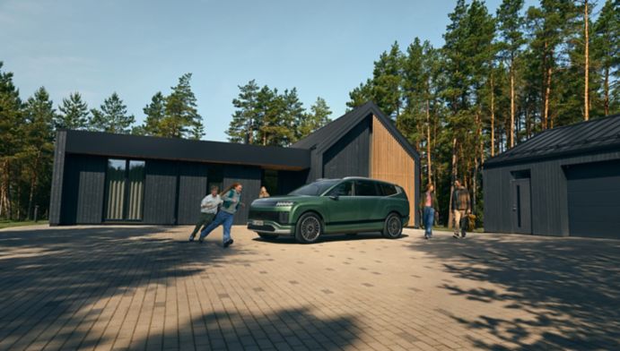 Rodicia a deti okolo zeleneho Hyundai IONIQ 9 pred rodinnym domom