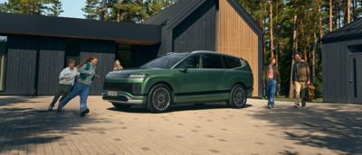 En barnfamilj går mot en parkerad Hyundai IONIQ 9 elbil.