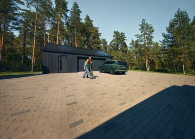 A Hyundai IONIQ 9 standing outside of a garage, with two persons walking by.