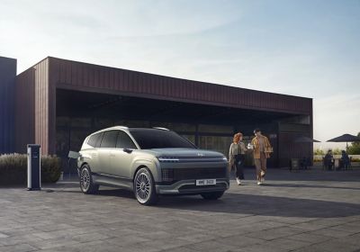 Vooraanzicht van de nieuwe Hyundai IONIQ 9 aan een lader voor een gebouw.