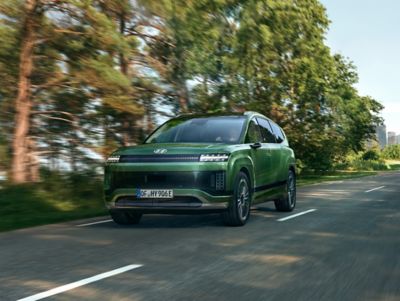 Hyundai IONIQ 9 driving through a natural landscape, highlighting electric SUV performance.