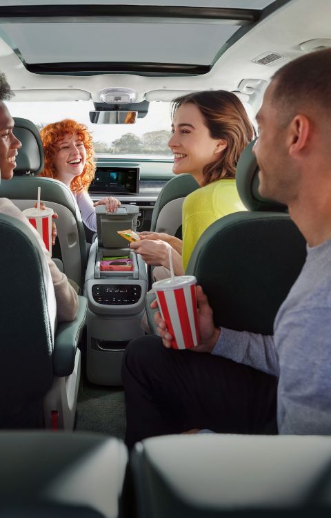 Four people in the Hyundai IONIQ 9 interior sharing snacks and drinks.
