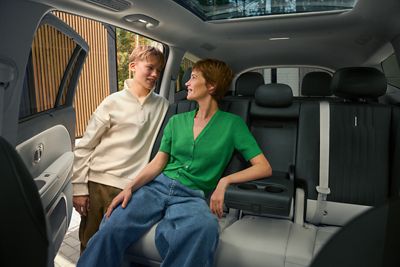 A person sitting in the Hyundai IONIQ 9 talking to a person standing outside of the car.