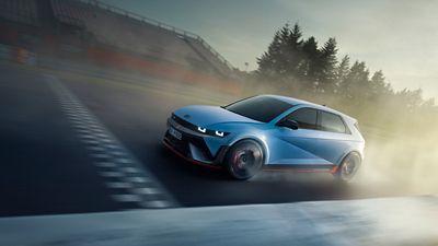 The all-electric Hyundai IONIQ 5 N driving on a race track with some trees.