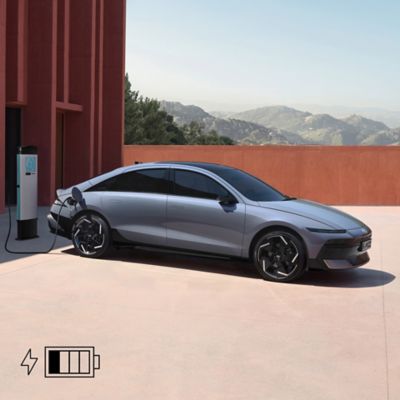The Hyundai IONIQ 6 electric sedan plugged into charge with mountains in the background.