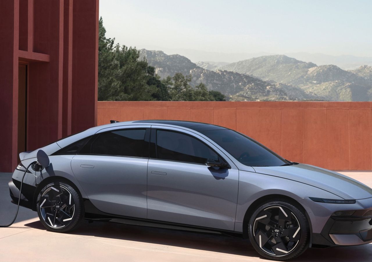 La berline électrique Hyundai IONIQ 6 branchée pour se recharger avec des montagnes en arrière-plan.