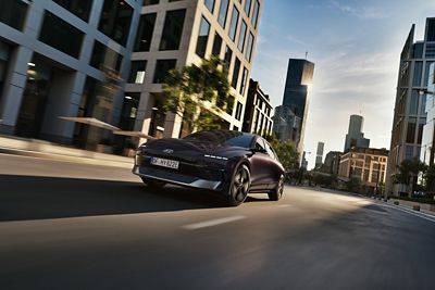 Hyundai IONIQ 6 driving through a modern city street.