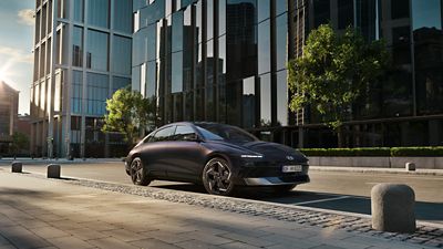 Hyundai IONIQ 6 electric car on a city street with glass buildings in the background.