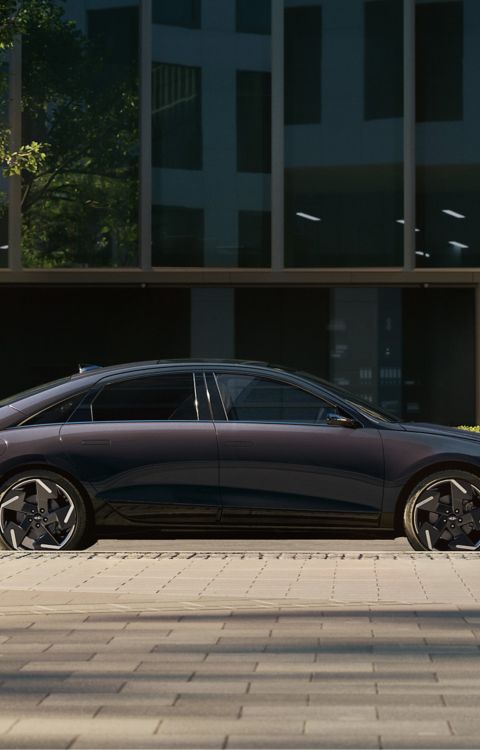 Hyundai IONIQ 6 electric sedan shown from street level parked with modern building in background.