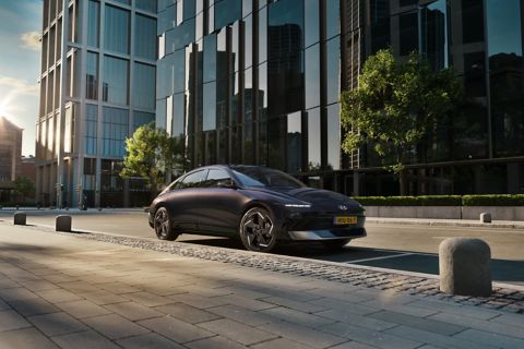 De elektrische Hyundai IONIQ 6 van opzij gefotografeerd in een straat met hoge gebouwen.