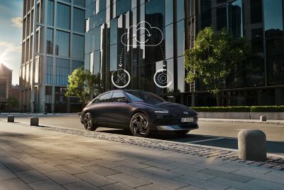 Hyundai IONIQ 6 electric sedan shown from the side parked on a city street with high rise buildings.