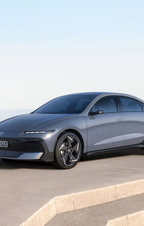 Hyundai IONIQ 6 parked near a waterfront with mountains in the distance.