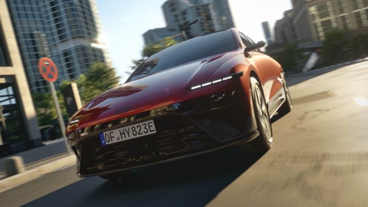 A red Hyundai IONIQ 6 N Line driving down a city street.