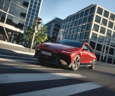 Ein roter Hyundai IONIC 6 fährt dynamisch durch eine Stadtlandschaft