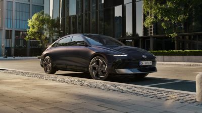 Der Hyundai IONIQ 6, von der Seite betrachtet, steht vor einem modernen Gebäude. 