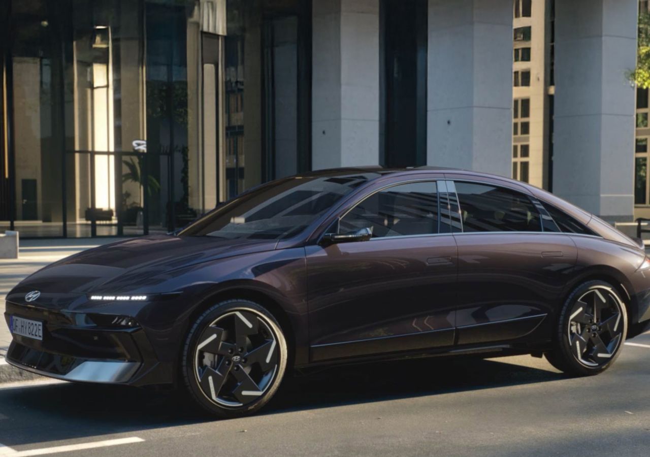 Hyundai IONIQ 6 elektrický sedan zachycený z boku před moderní budovou.