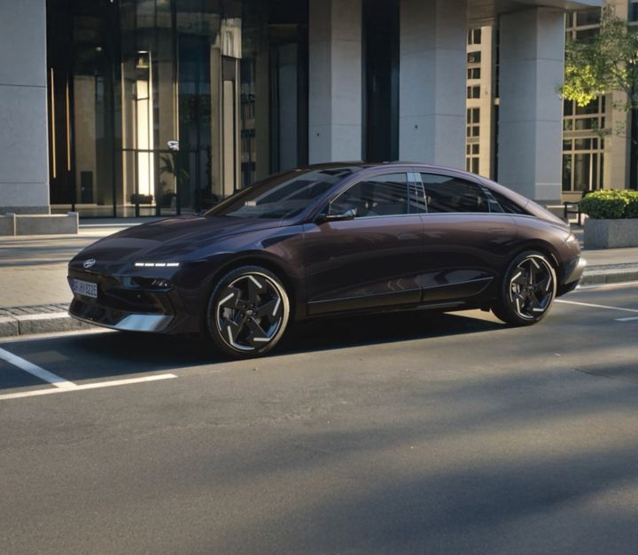 Hyundai IONIQ 6 electric sedan shown from the side in front of a modern building.