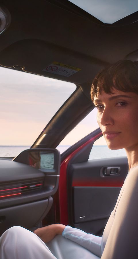 A woman in the front passenger seat of the Hyundai IONIQ 6 with a man leaning on the open door.