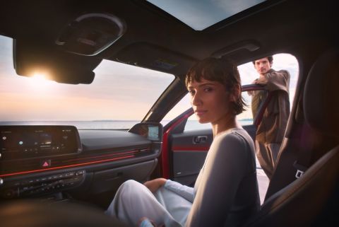 A woman in the front passenger seat of the Hyundai IONIQ 6 with a man leaning on the open door.