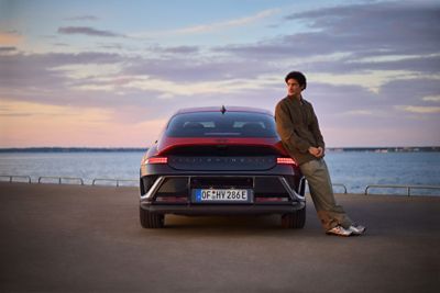 A man leaning on the side of a Hyundai IONIQ 6 N Line parked next to the ocean.