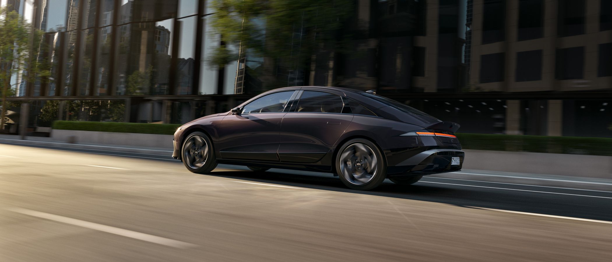 Hyundai IONIQ 6 electric sedan shown from the side driving on a city street.