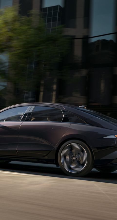 Hyundai IONIQ 6 Elektro-Limousine von der Seite gezeigt, wie sie auf einer Stadtstrasse fährt.