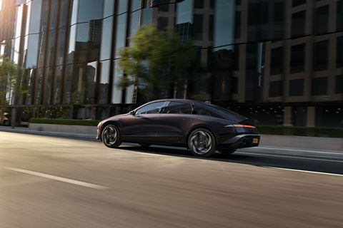 Een elektrische Hyundai IONIQ 6 van opzij gefotografeerd rijdend door een stadsstraat.