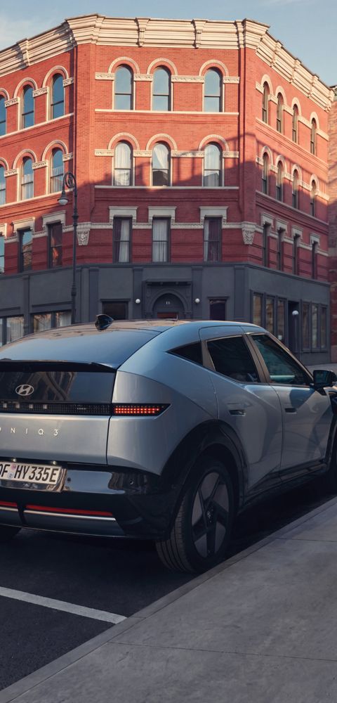 Hyundai IONIQ 3 zaparkovaný a nabíjející se u městského chodníku.