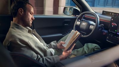 Hyundai IONIQ 3 interior with driver reading a book in the front seat.