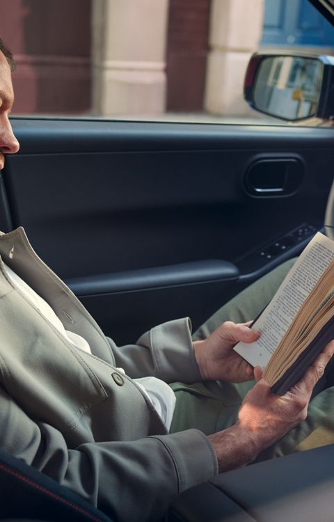 Interior del Hyundai IONIQ 3 con el conductor leyendo un libro en el asiento delantero.