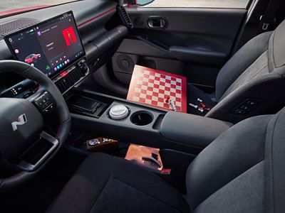 Het interieur van de Hyundai IONIQ 3 met zicht op de middenconsole en een houten schaakbord op de passagiersstoel.