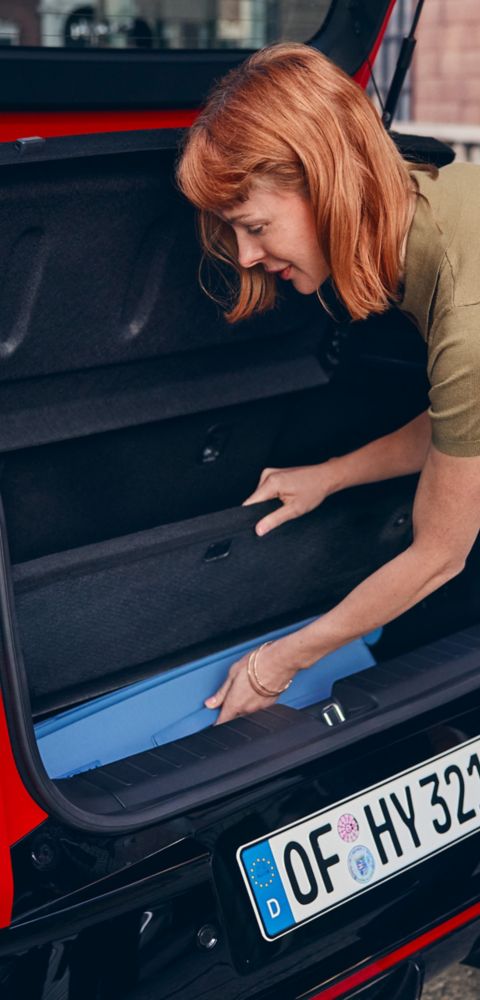 A woman loading items into the Hyundai IONIQ 3’s Megabox trunk floor storage space.