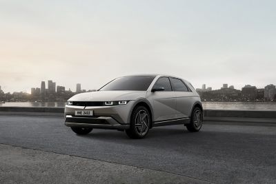 The all-electric Hyundai IONIQ 5 seen from the front parked by modern building.