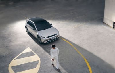Three quarter view of the new Hyundai IONIQ 5 seen from above, parked, and a man walking away